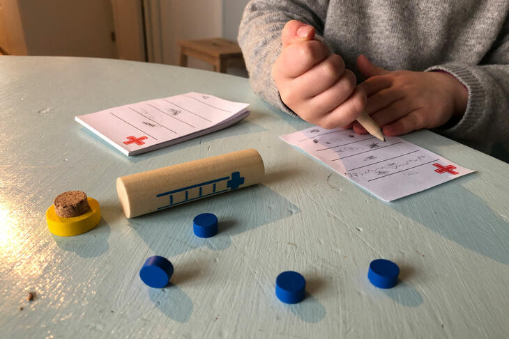 barnehender skriver på lekeresept og ekse med lekemedisiner ligger på bordet.