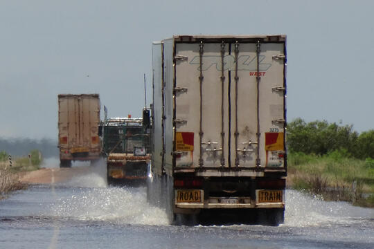 lasterbiler som kjører på oversvømmet vei